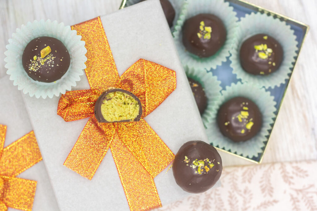Assorted Dubai pistachio truffles in and on top of a box with a bow