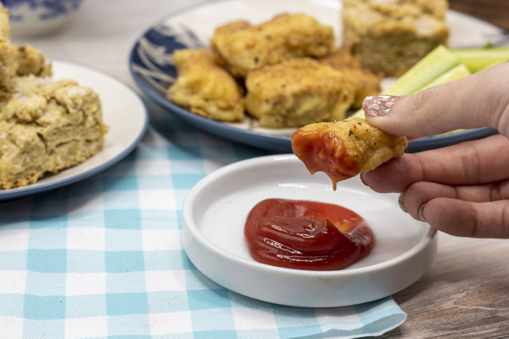 dipping gluten-free fish stick into ketchup