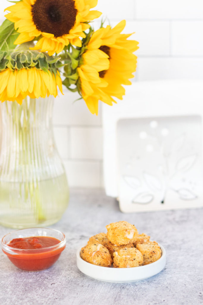 fried cubes of cheese by marinara sauce and sunflowers