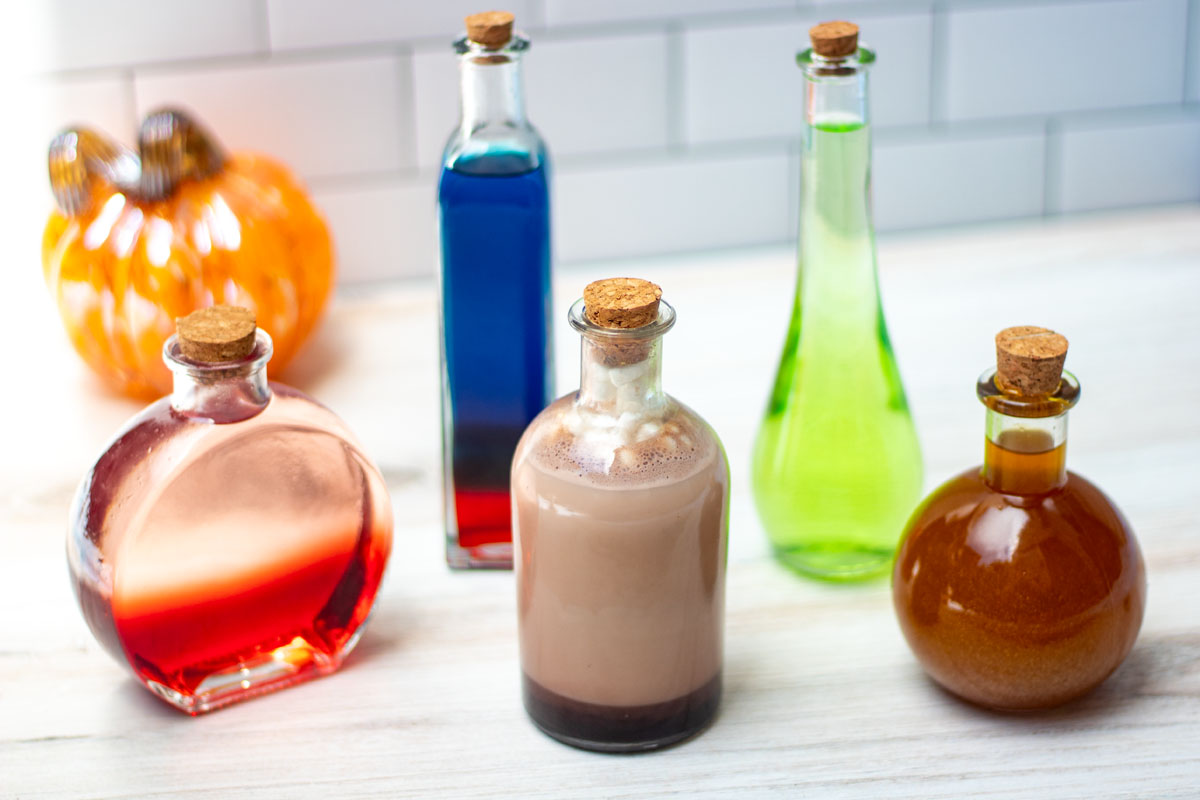 Five colorful halloween cocktails in varying potion bottles