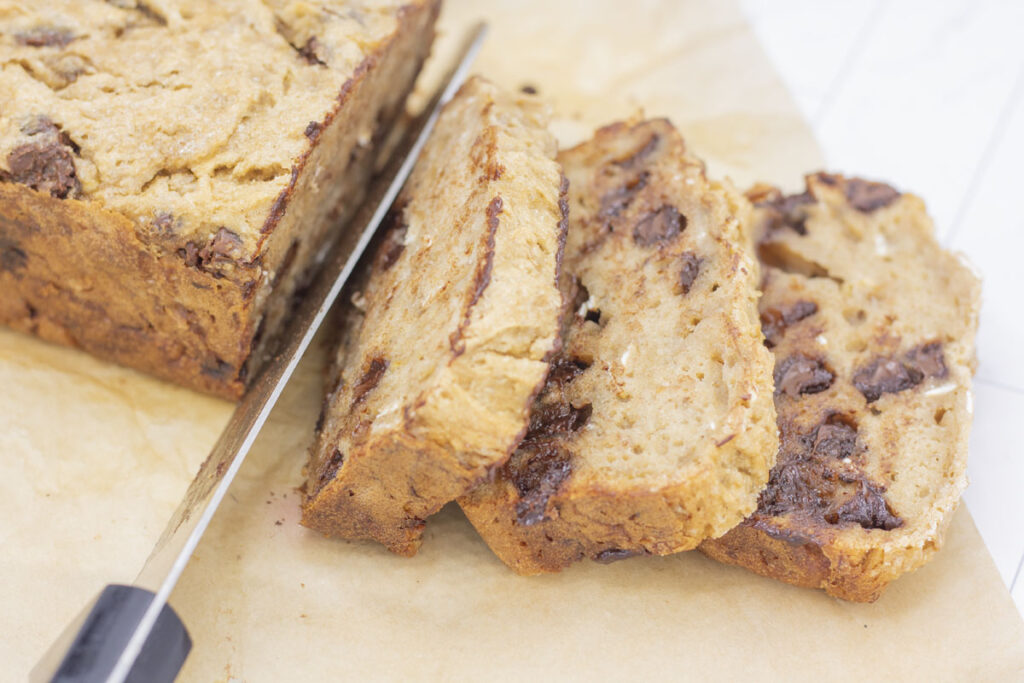 Knife slicing fresh chocolate chip banana bread