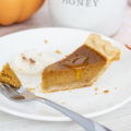 A fork lying next to pie with honey dripping down on it