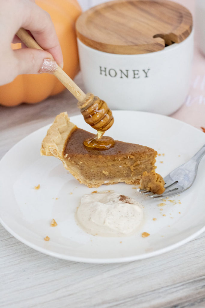 honey dipper dripping honey onto pumpkin pie
