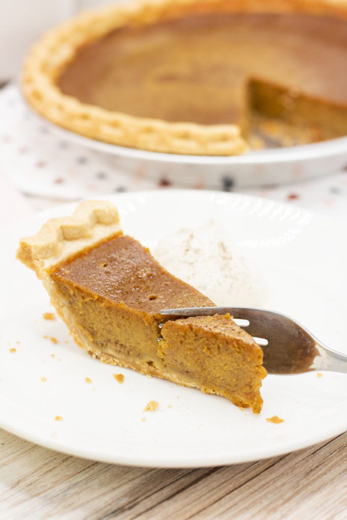 Fork cutting into a slice of caramelized pumpkin pie