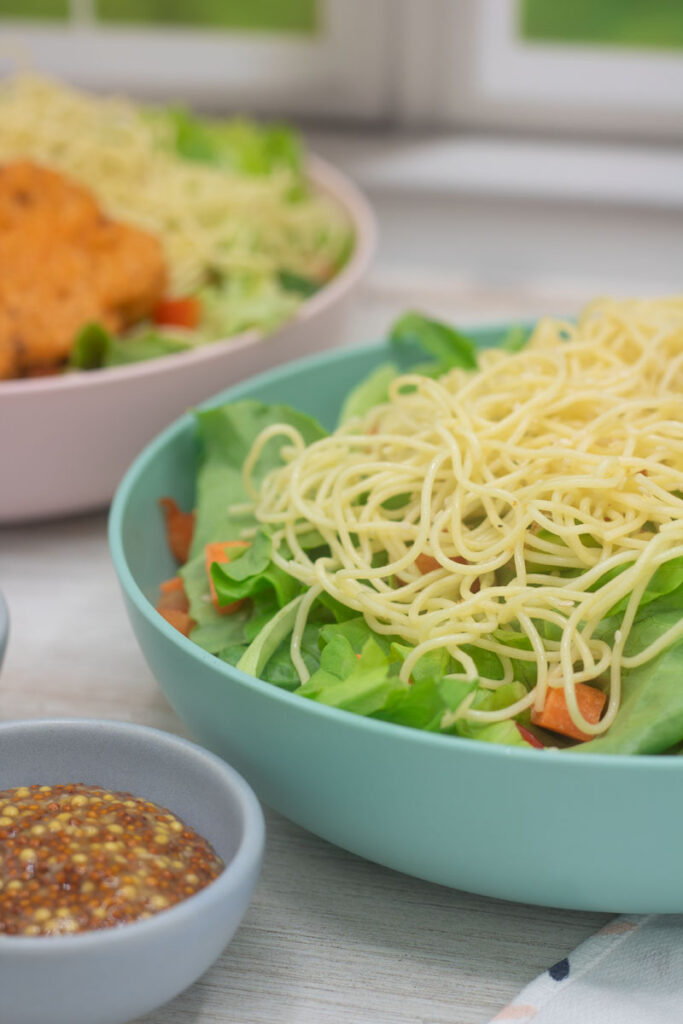 Lettuce greens topped with angelhair pasta and a side of whole grain mustard