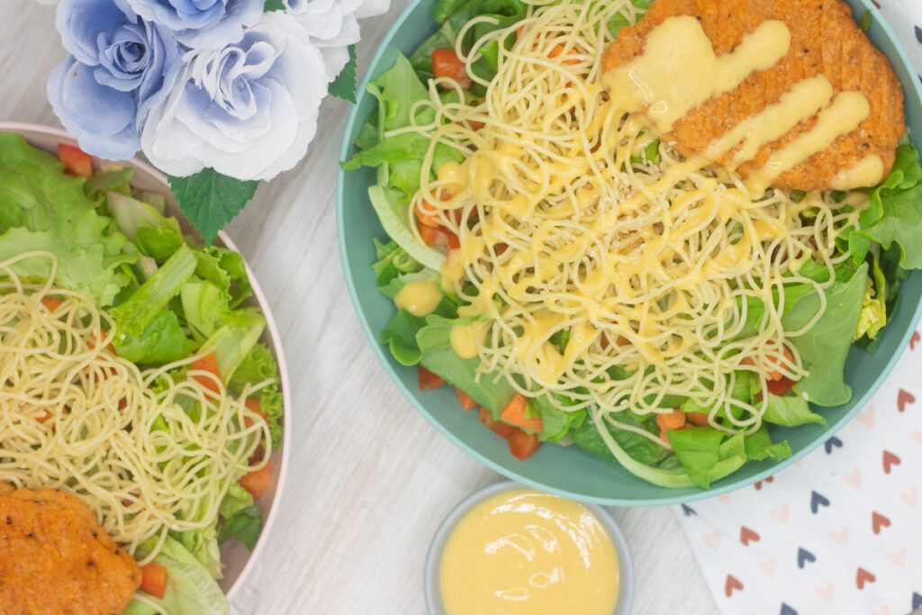 Two bowls of Joe's honey mustard salad, topped with angelhair pasta and a breaded chicken cutlet