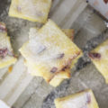 Lemon cake bars with strawberries stacked on a plate