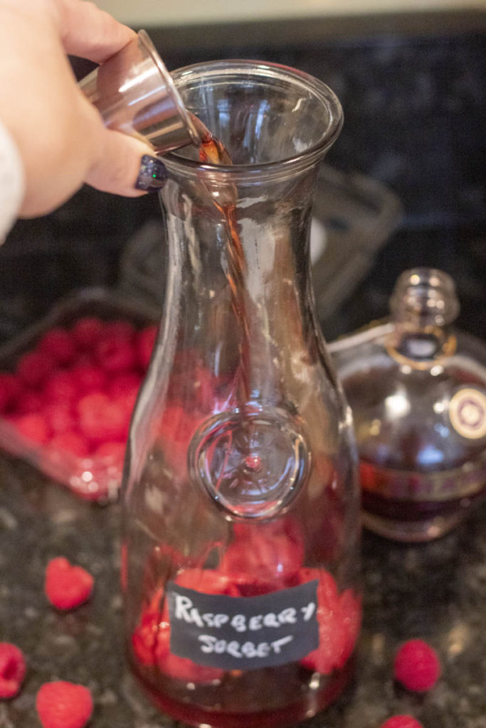 pouring chambord into raspberry sorbet mimosa for your NYE cocktails