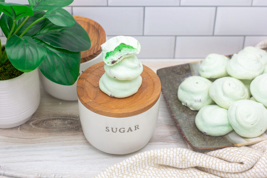 Assorted mint chocolate chip meringues stacked on a sugar canister