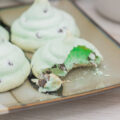 A broken mint chocolate chip meringue on a plate with other meringues