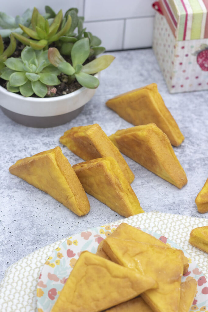 Staggered triangles of sweet corn mochi cornbread next to a plate of cornbread