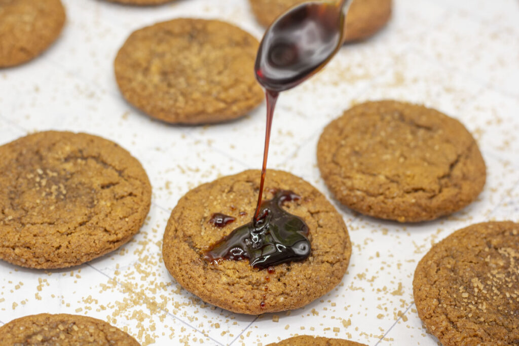 Spoon drizzling molasses on top of molasses cookies