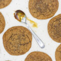 A spoon smeared with molasses surrounded by molasses cookies