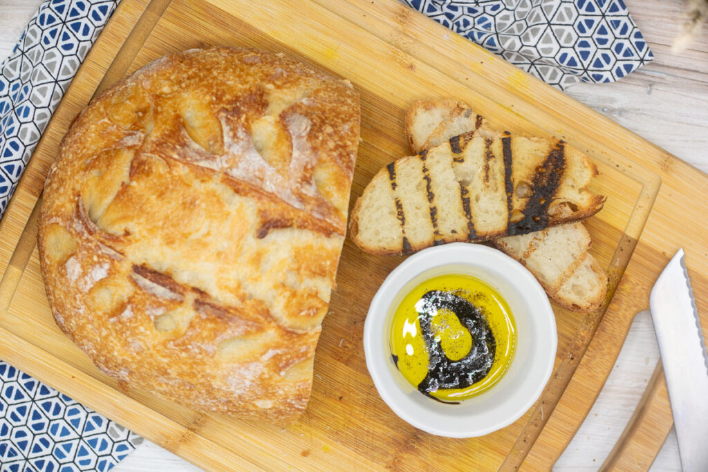 No knead sourdough bread with grilled slices alongside dipping oil