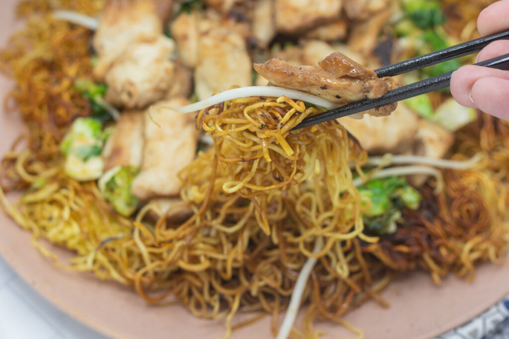 Chopsticks holding pan-fried noodles.