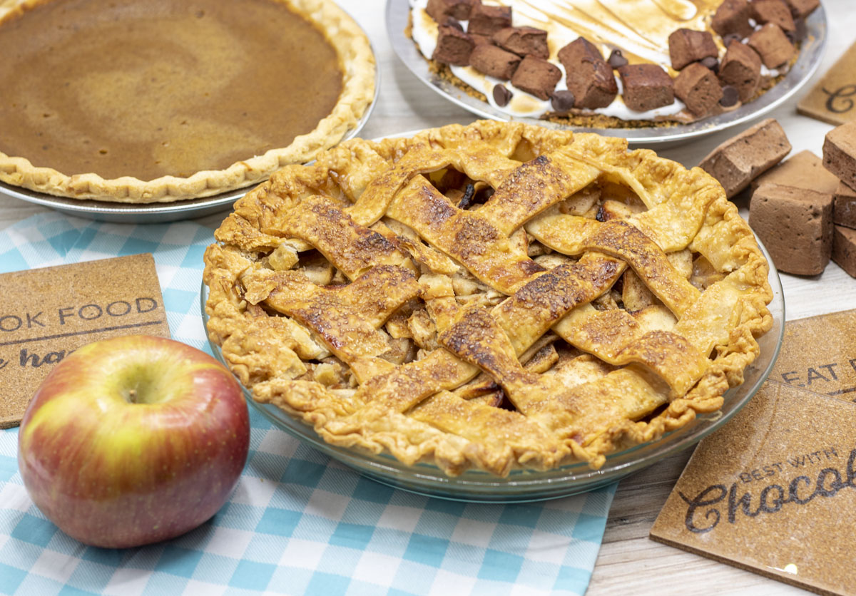 Lattice apple pie beside two other holiday pies