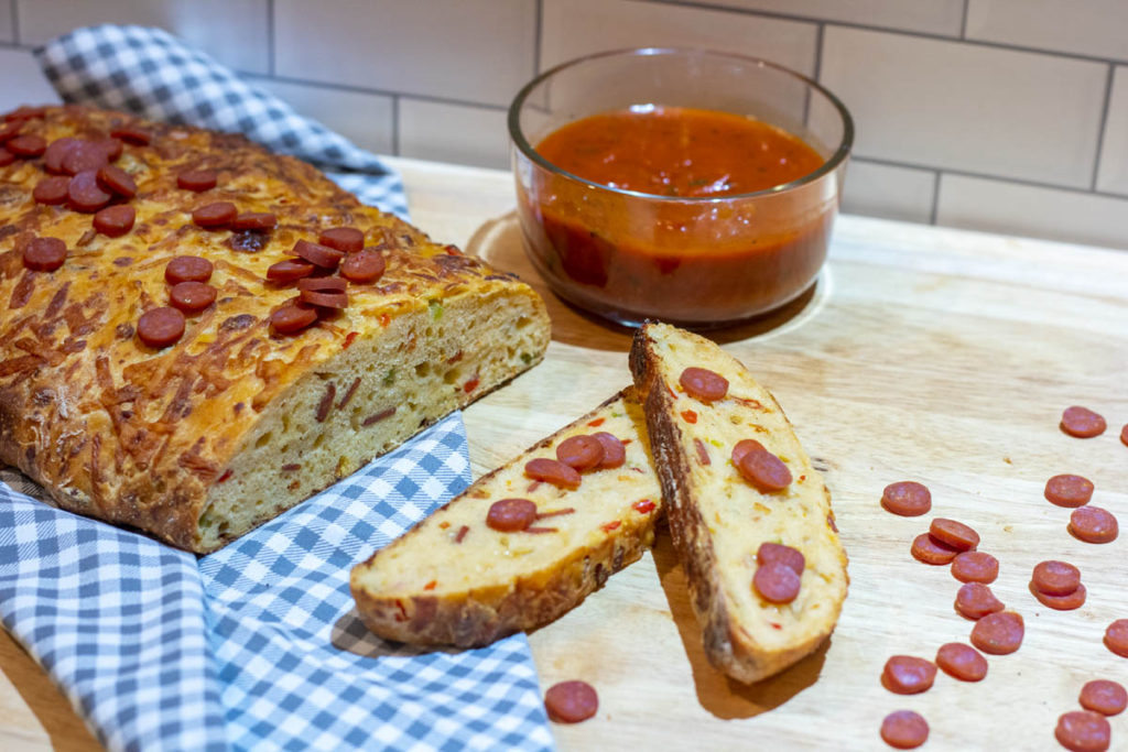 Slices pizza loaf with pepperonis scattered around