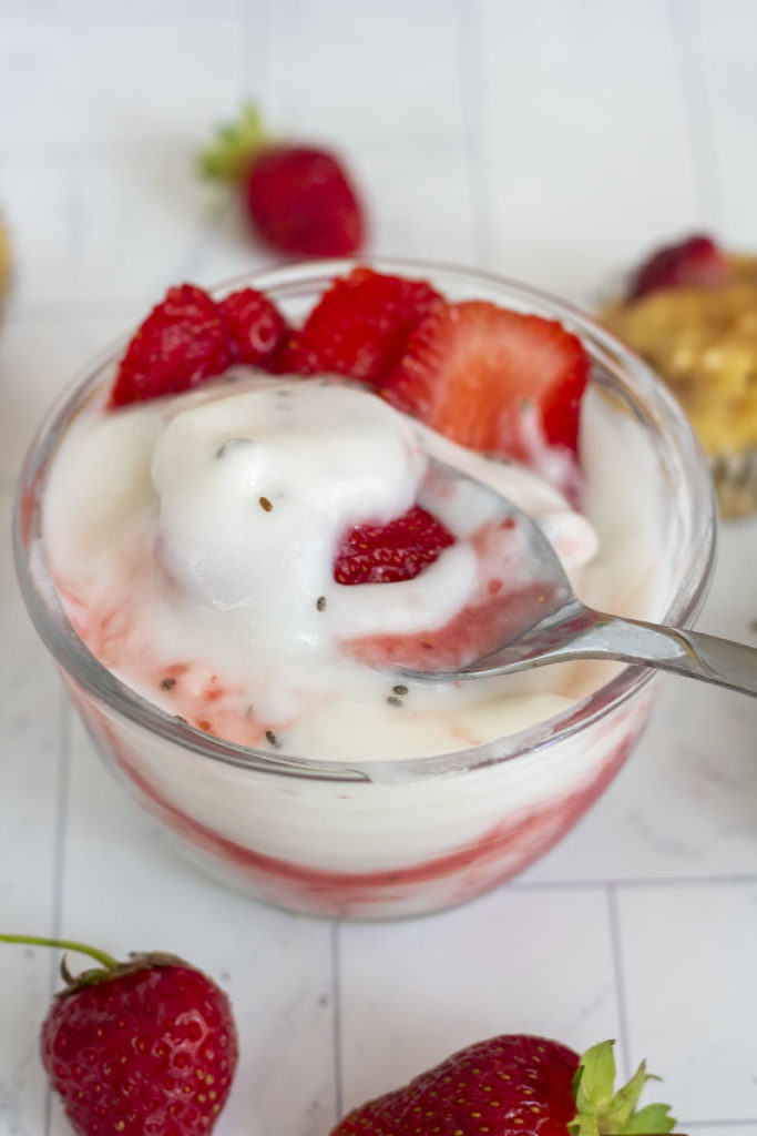 Spoon scooping strawberries and cream protein yogurt