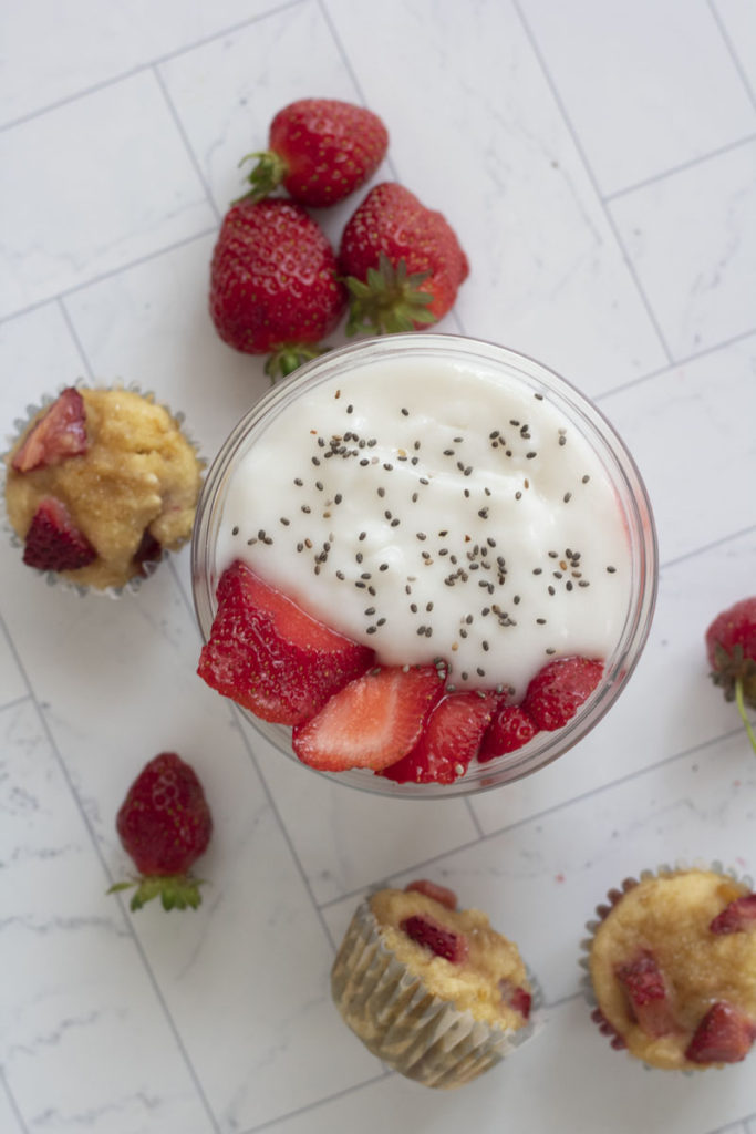 birds eye view of strawberries and cream protein yogurt surrounded by mini muffins