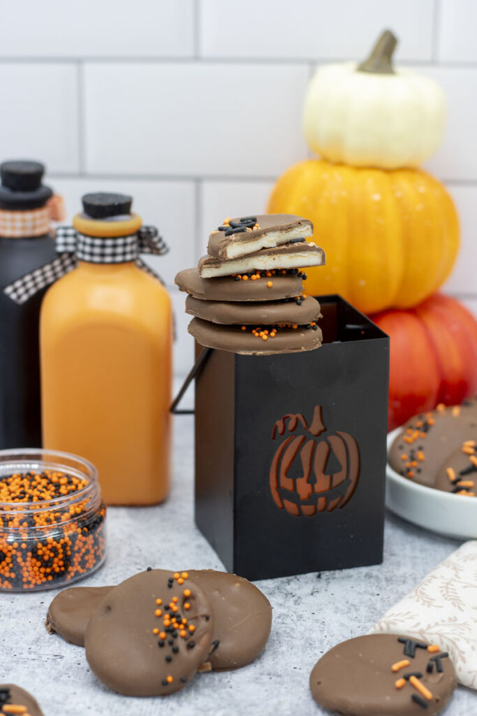 Pumpkin spice chocolate patties stacked on a halloween votive with patties scattered around