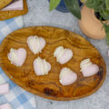 Heart shaped raspberry marshmallows drizzled with white chocolate on a small wooden plate