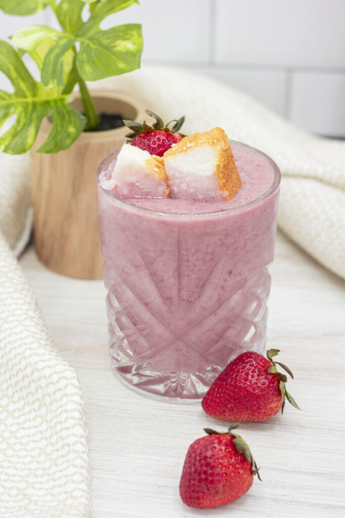 Glass of reverse strawberry shortcake topped with cake and strawberries