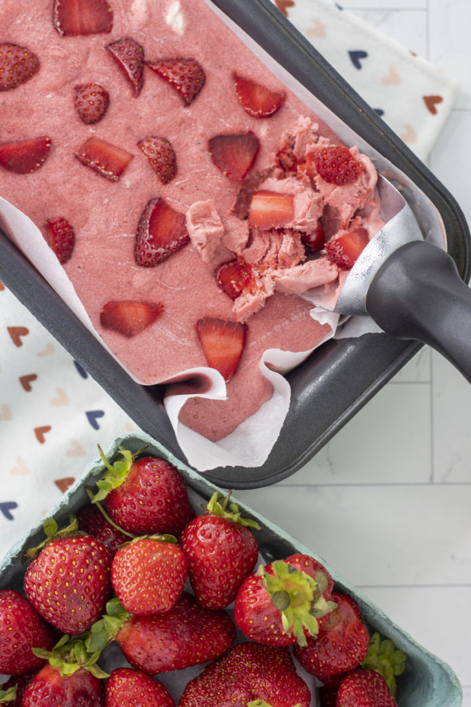 ice cream scoop in a pan of no churn roasted strawberry ice cream