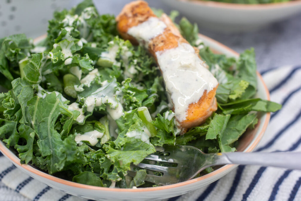Salmon Kale Caesar Salad with a drizzle of caesar dressing