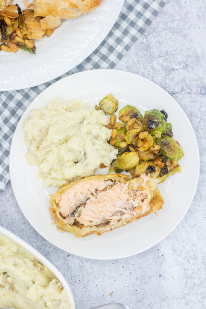 Plate of salmon en croute beside brussels sprouts and mashed potatoes
