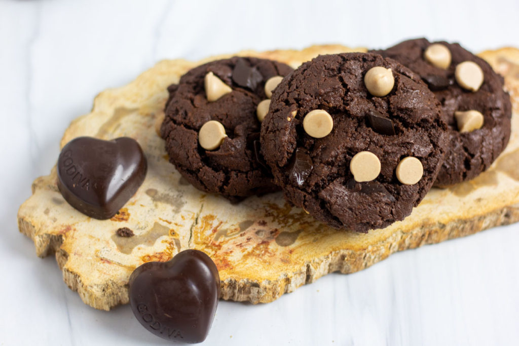 salted caramel chip chocolate cookies on a petrified wood slab with chocolates