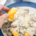 Dipping biscuit into chunky sausage gravy