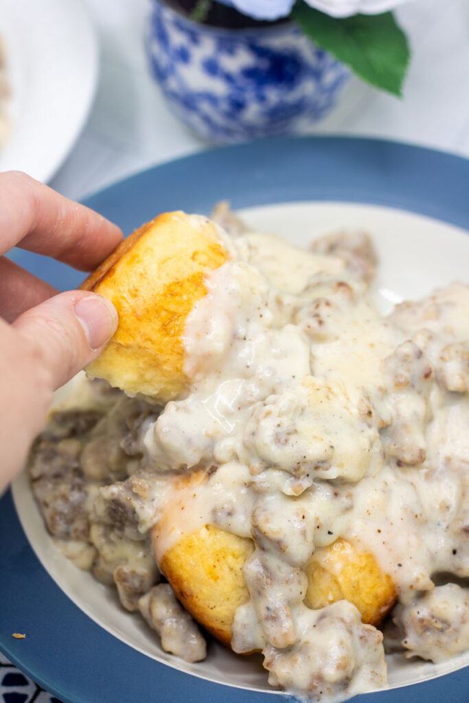 Dipping biscuit into chunky sausage gravy