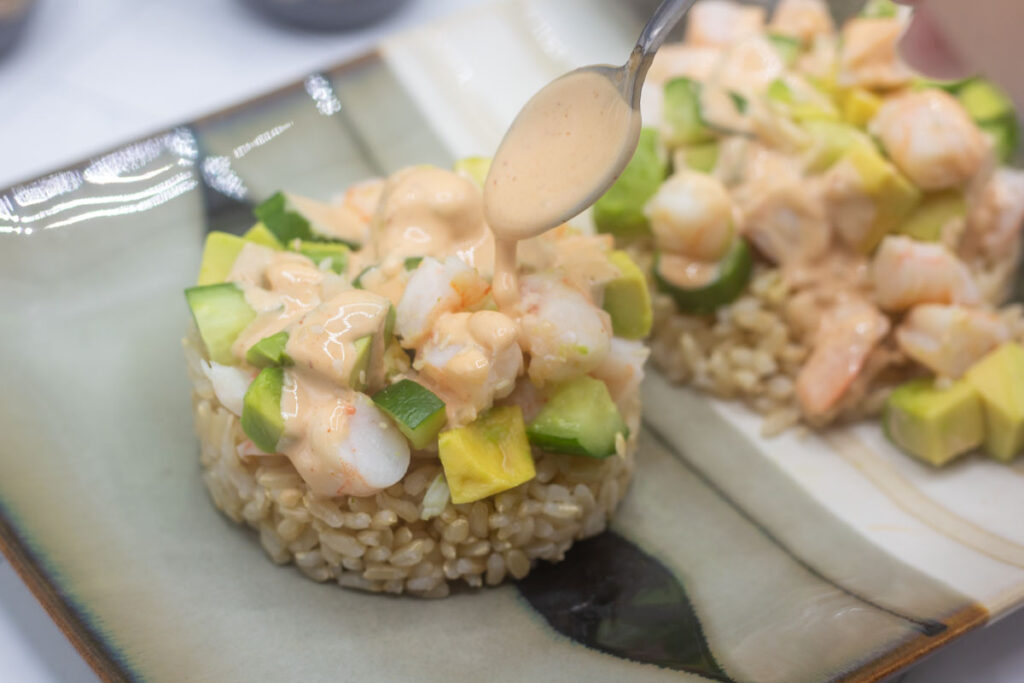 Drizzling sriracha mayo onto shrimp stacks