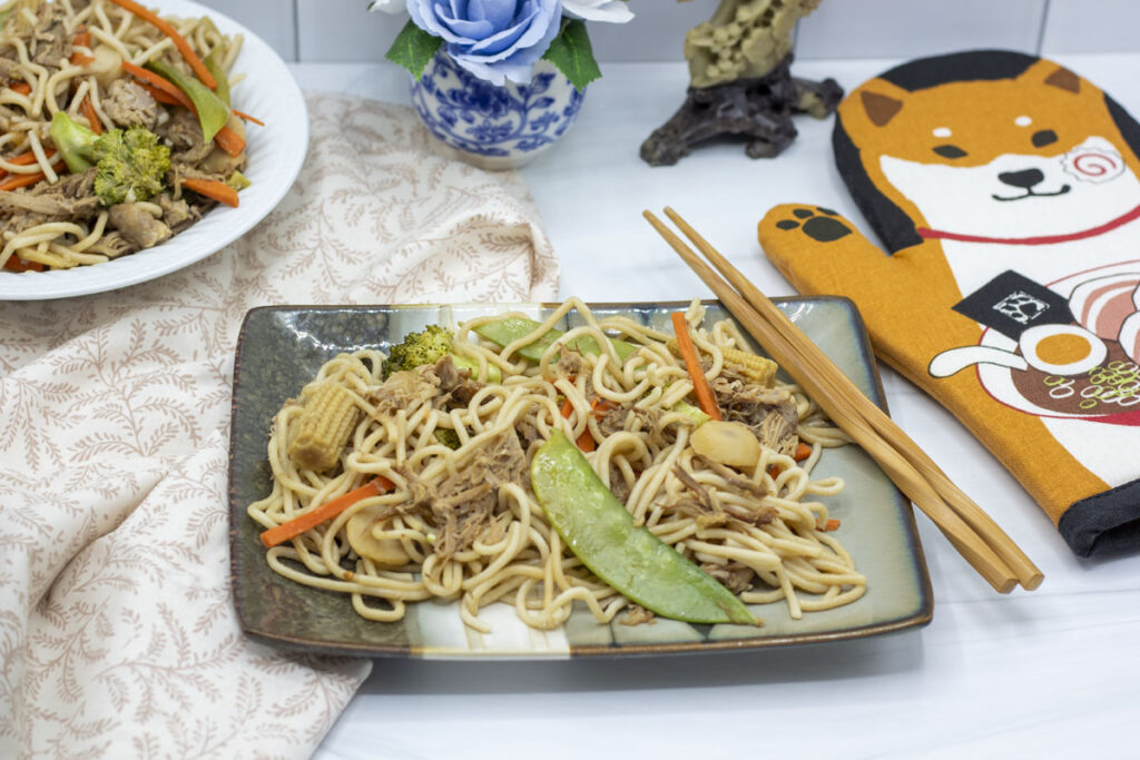 Slow cooker lo mein with chopsticks resting on the plate