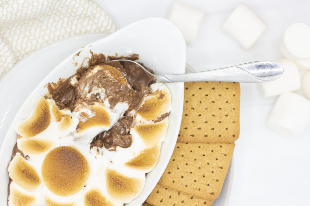 Spoon digging into s'mores chocolate and marshmallow dip