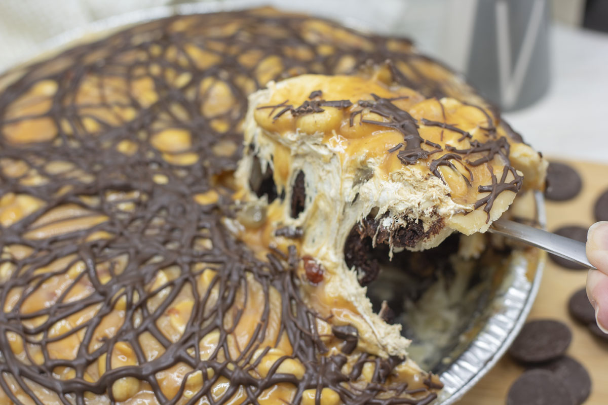 Lifting a slice of snickers brownie pie from the pie plate