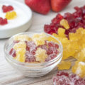 sour gummies in a bowl next to cherry and lemon gummies