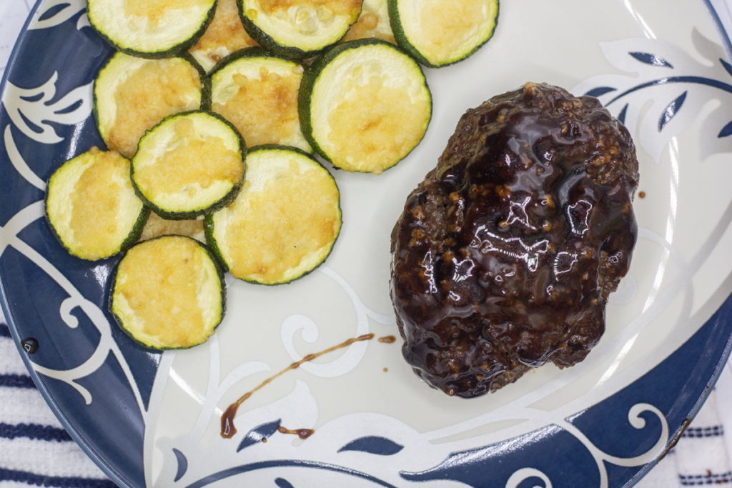 soy glazed meatloaf on a plate with zucchini