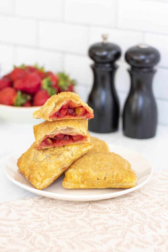 A stack of strawberry apple hand pies, one cut open
