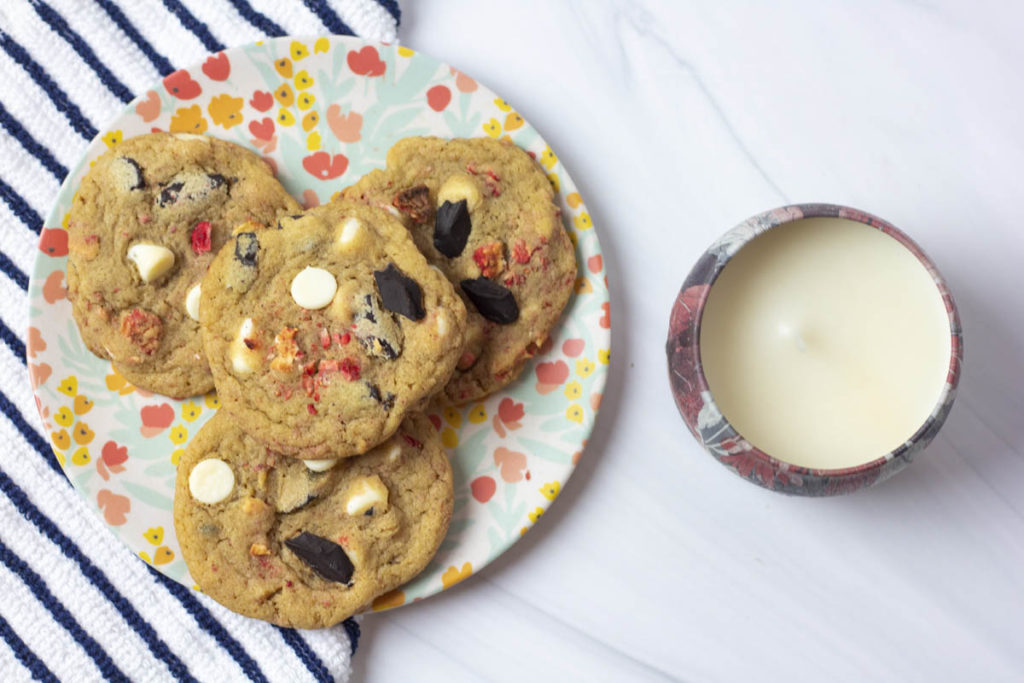 Strawberry chocolate chunk cookies on a flowery plate next to a candle