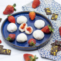 strawberries, mochi, and chocolate on a blue plate