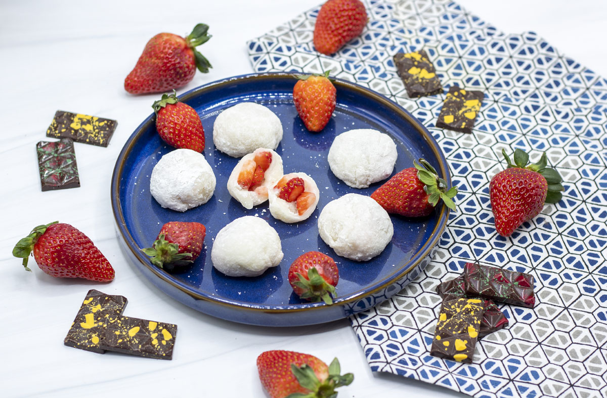 strawberries, mochi, and chocolate on a blue plate