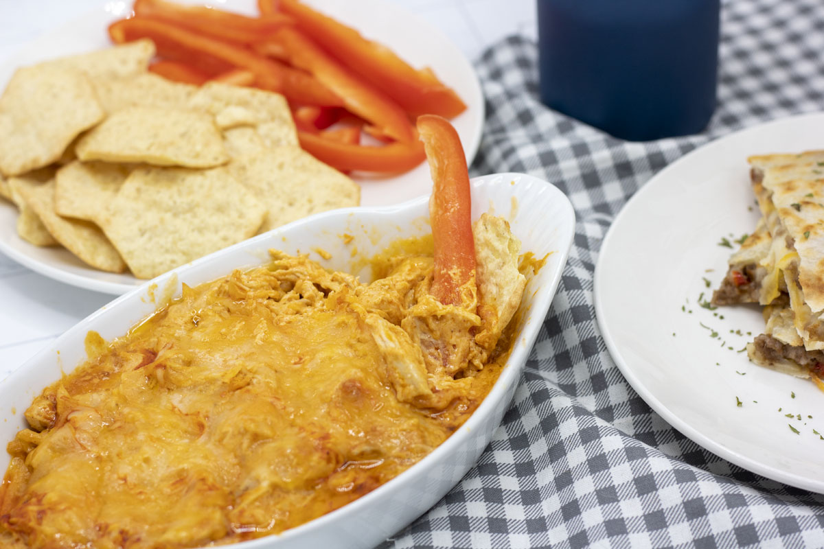 Red bell pepper dipping into buffalo chicken dip