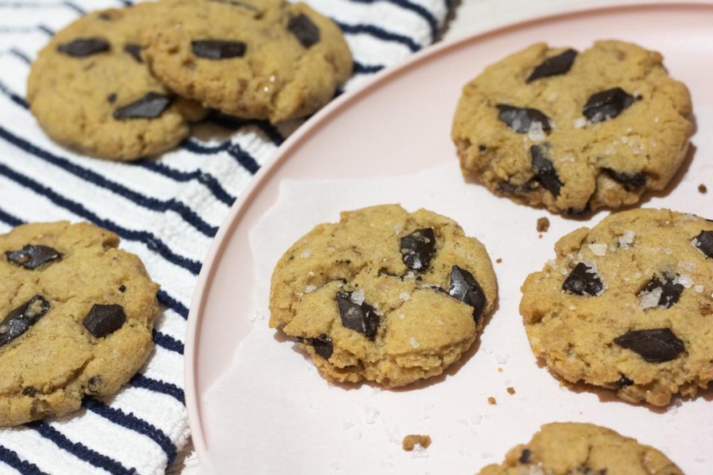 brown butter toffee chocolate chip cookies on a plate and scattered around