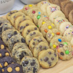 A variety of cookies on a wooden cutting board