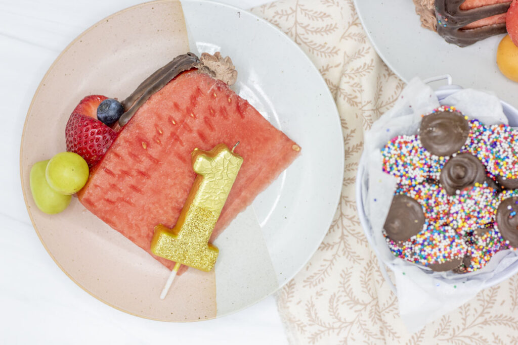 Slice of no sugar watermelon cake with a large #1 candle alongside