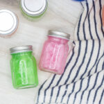 Assorted pink and green cocktails in tiny mason jars